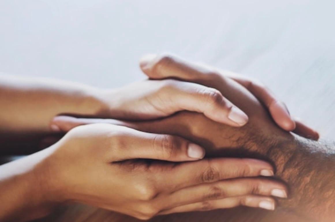 Two people holding hands, offering comfort and support